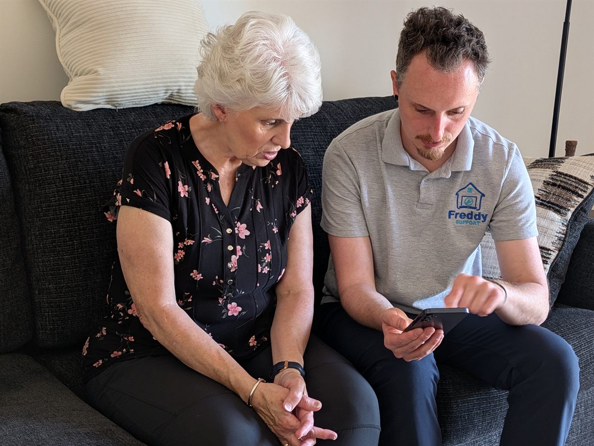 Freddy helping a client with her phone at home